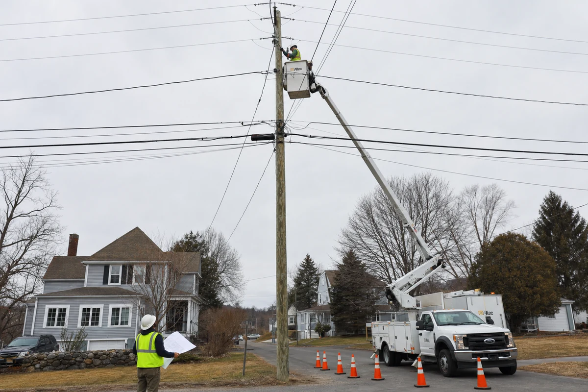 Telecom field workers performing make-ready pole rearrangement with bucket truck