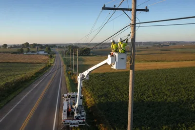 Electric cooperative lineman reviewing aerial fiber route map on a tablet mounted on a utility truck